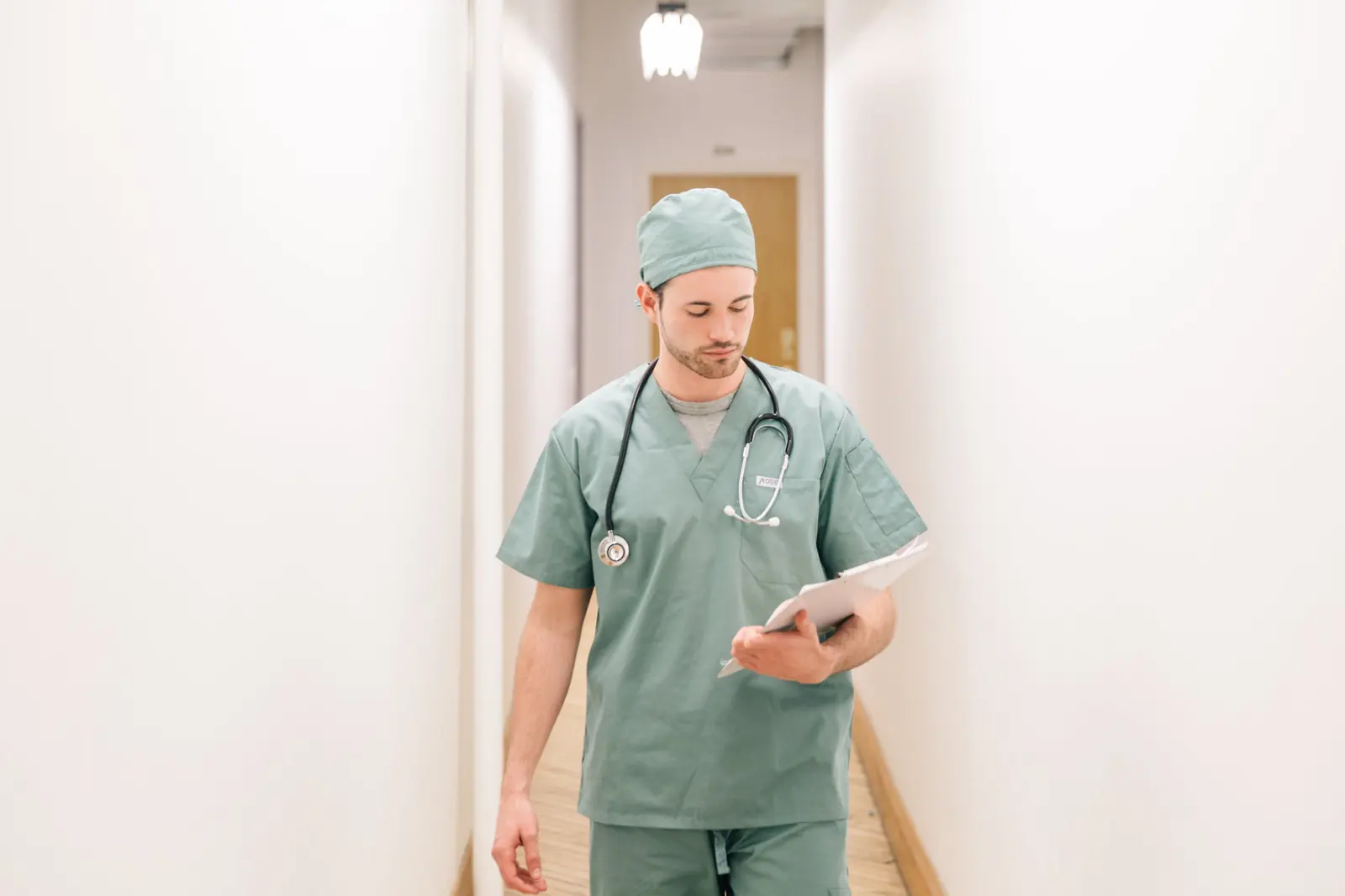 Klinik koridorunda tablete bakarak yürüyen bir hekim