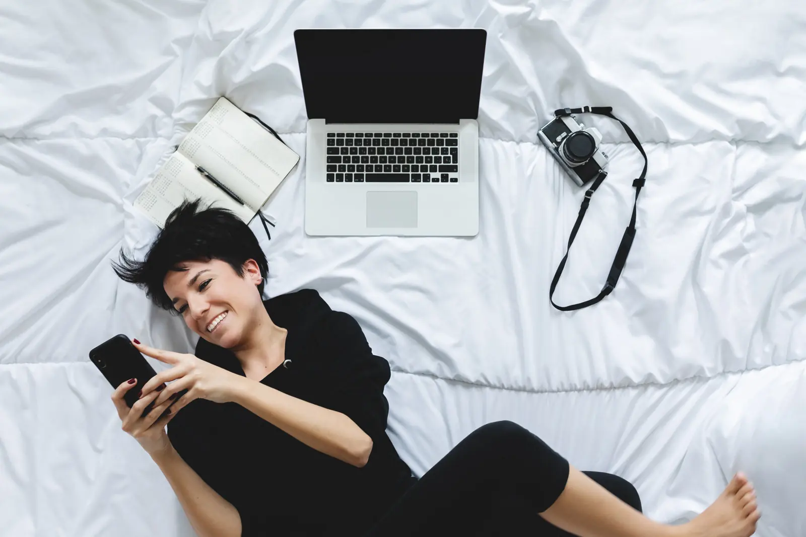 A woman messaging from her phone in bed at night
